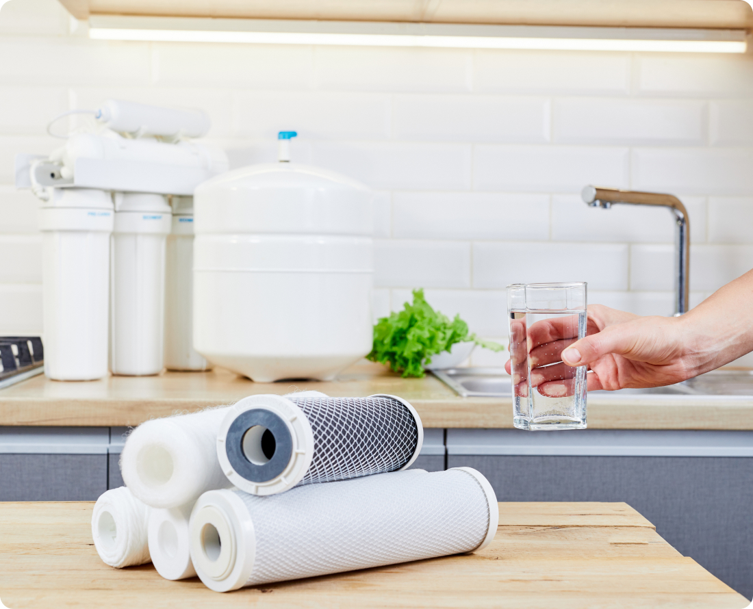 Water filters and a glass of clean water on a kitchen counter with a faucet and sink.