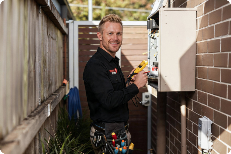 Electrician testing an electrical panel with a yellow meter.