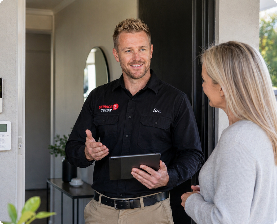 Service technician Ben from Service Today discusses security with a homeowner, holding a tablet.