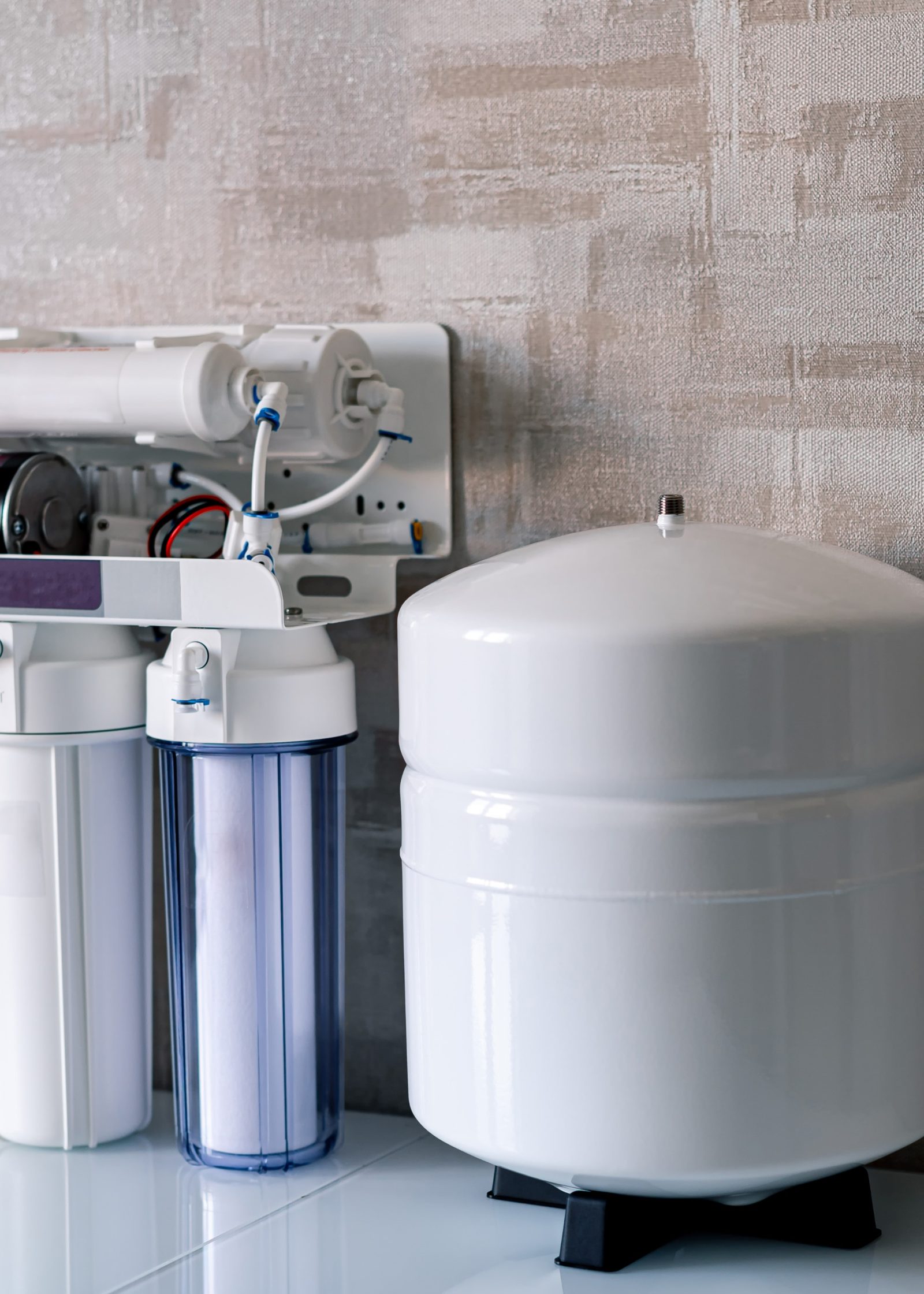 Water purification system with filters and storage tank against textured wall.