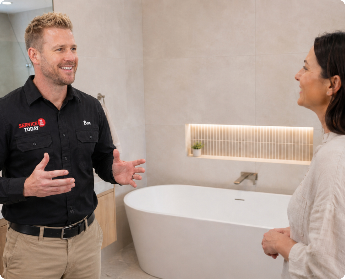 Two people discussing a bathroom remodel, one pointing to an open area.