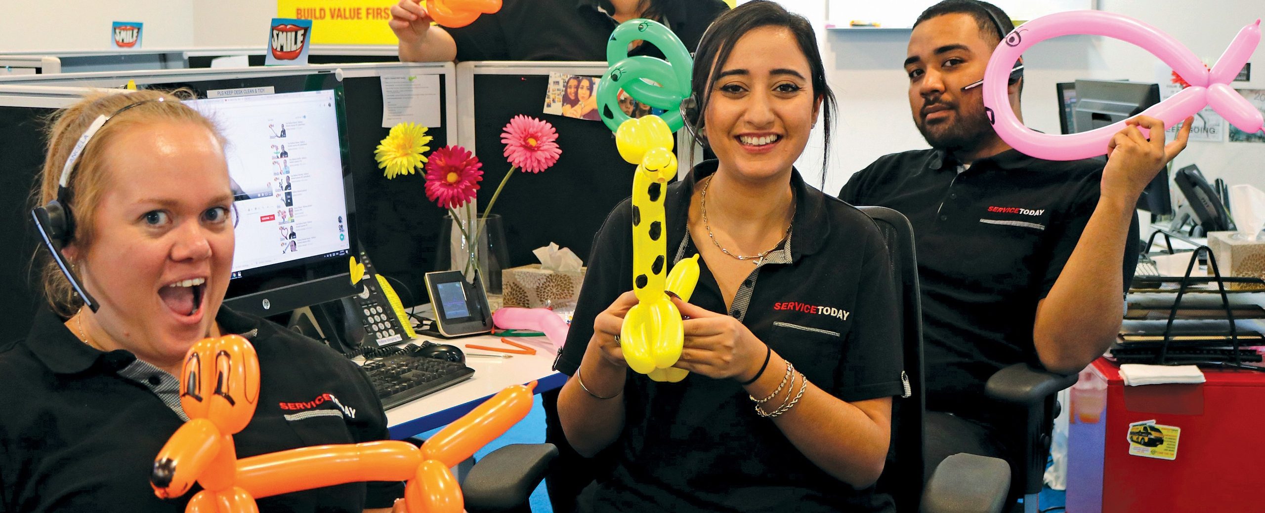 Employees at Service Today office playing with balloon animals in a fun and lighthearted moment.