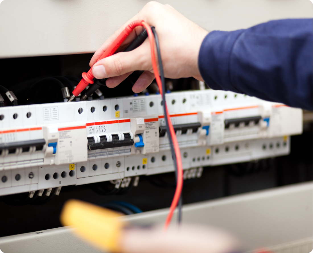 Electrician using a multimeter to test surge protection breakers in an electrical panel.