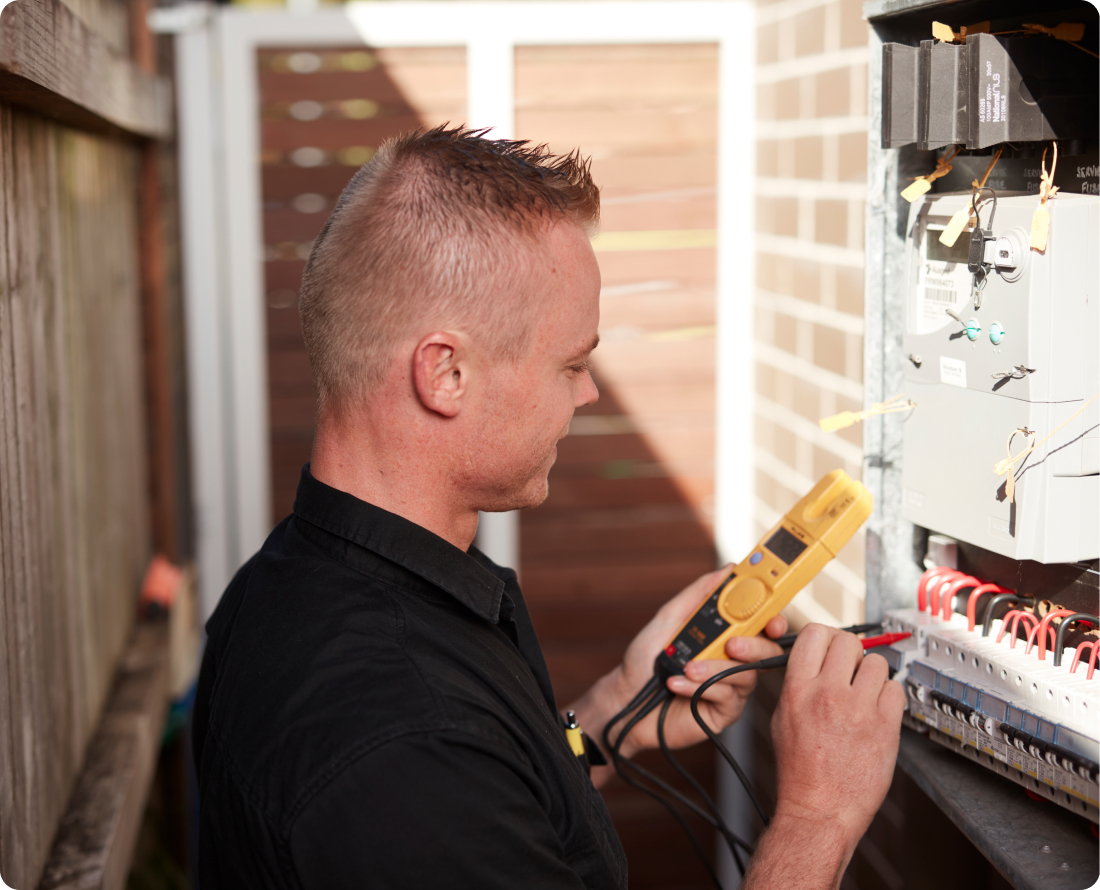 Electrician using a multimeter to test an electrical panel for surge protection.
