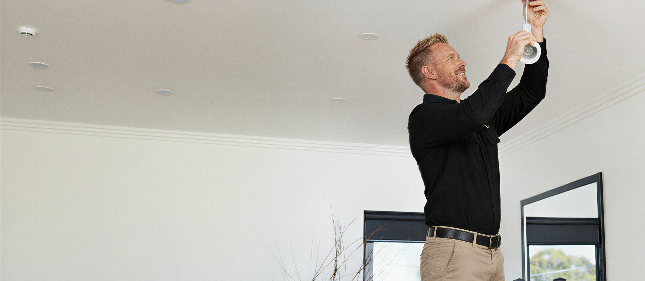 Man installing recessed ceiling light fixture.