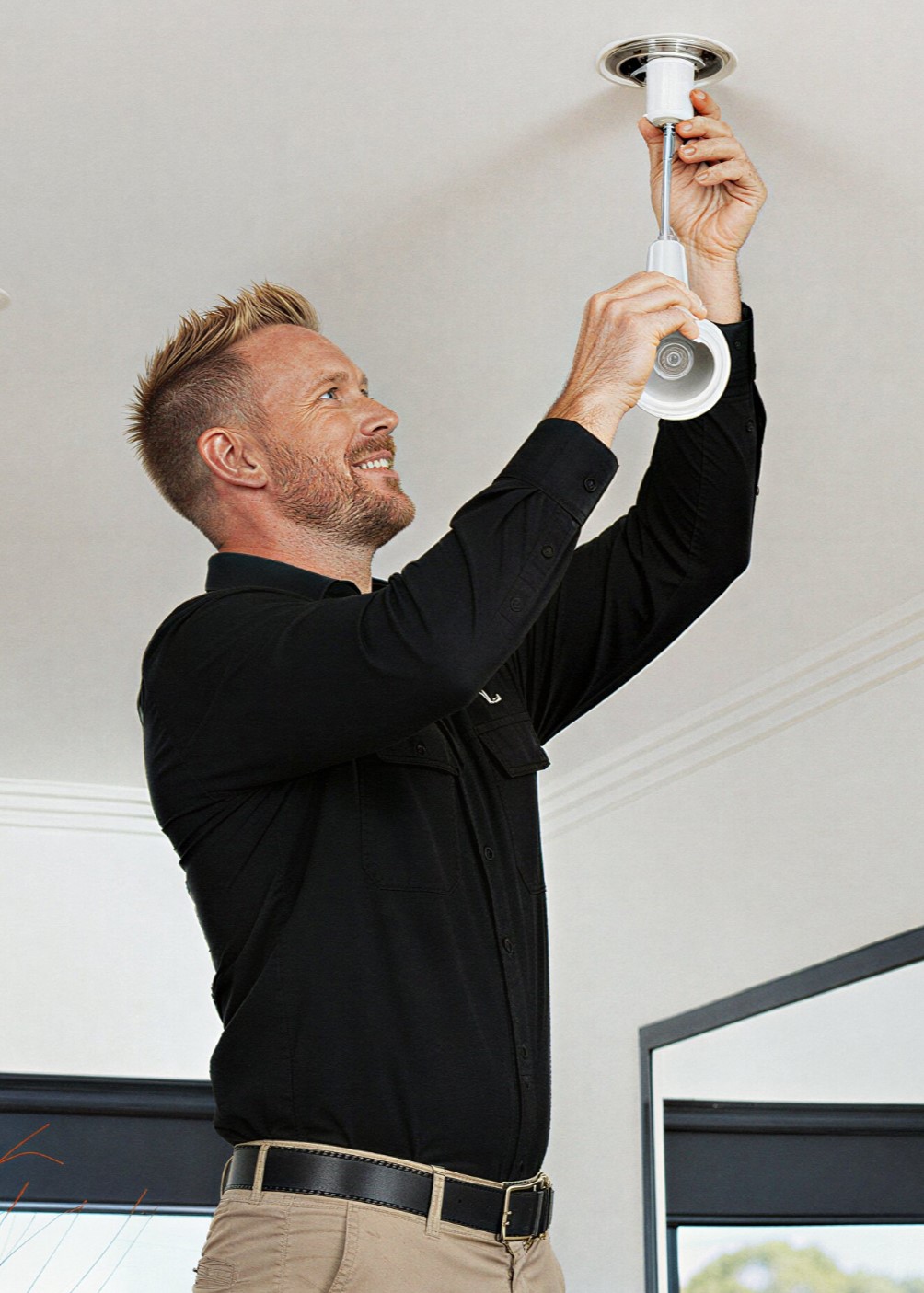 Man installing a ceiling light fixture.