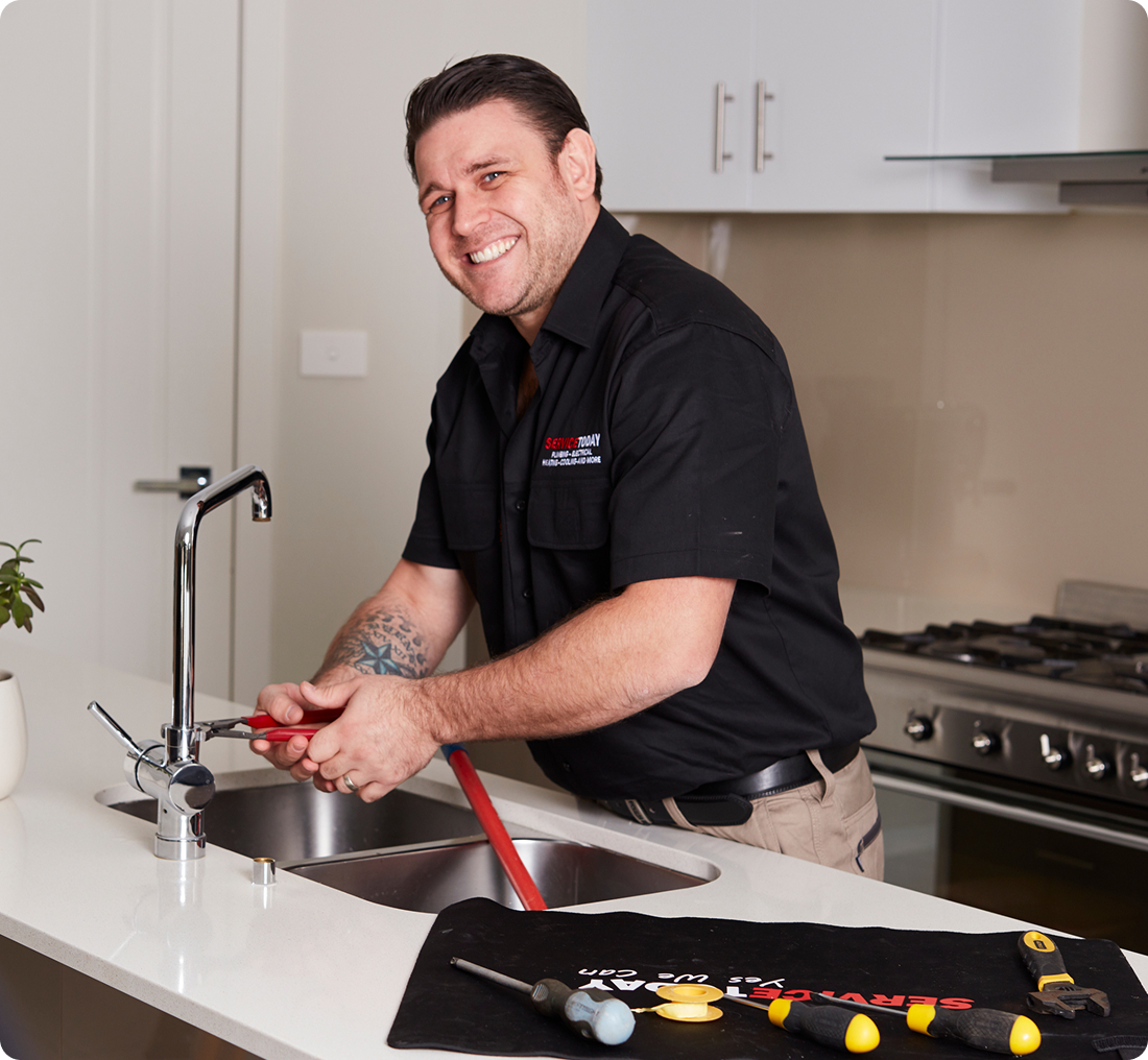 Plumber fixing kitchen sink with tools, ready to serve.